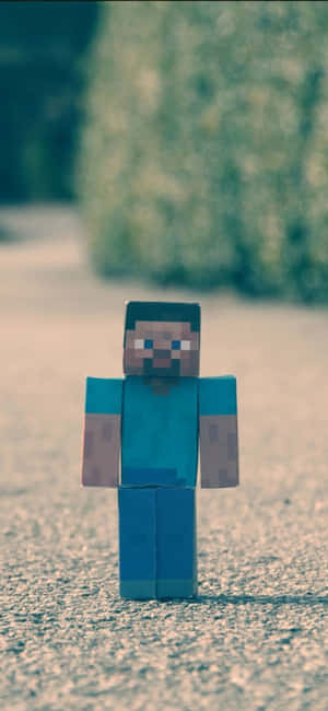 像素化Minecraft Steve公仔企喺室外碎石上面。 — iPhone 14 壁紙