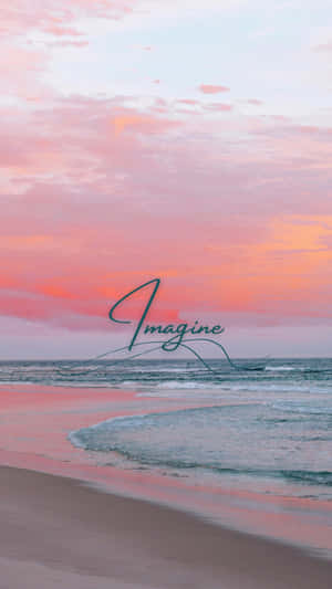 海洋上粉紅和橙色的日落，沙灘上寫著「Imagine」文字