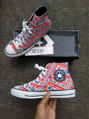 手拿紅白藍Converse All Star運動鞋，帶有標誌印花 — 3:4 壁紙