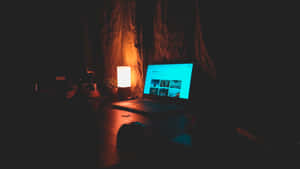 夜晚在黑暗的房間裡發光的筆記型電腦和燈。
