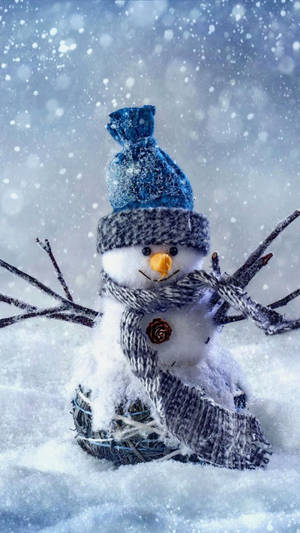 一個戴著藍色帽子和圍巾的雪人，在下雪時站在雪地裡。