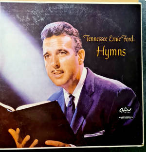 Tennessee Ernie Ford 身穿西裝，在聚光燈下手持讚美詩集。