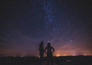 兩個人以星空為背景的剪影，銀河可見。