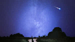 一個人站在星空下的路上，有流星