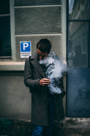 男子在街上吸電子煙，身穿灰色外套