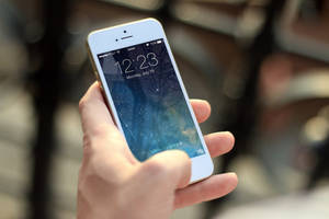 手拿著白色iPhone，帶有星空壁紙和解鎖提示。