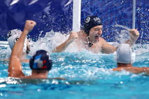 水球運動員在泳池中高舉拳頭慶祝勝利。