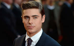 Zac Efron 在正式活動中穿著深色西裝和圖案領帶。