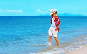 一個戴著太陽眼鏡和帽子的年輕男孩，在陽光明媚的海灘上走過海浪。