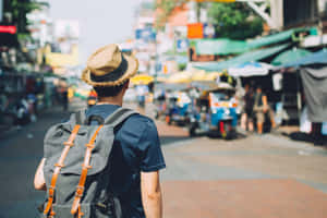 一個背著背包、戴著草帽的人穿過繁忙的街市。