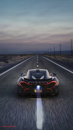 黑色McLaren在黃昏時分沿沙漠高速公路飛馳，尾燈發紅光。