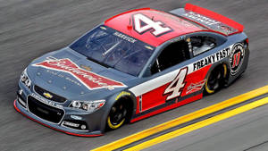 紅白灰色NASCAR賽車在賽道上疾馳，帶動態模糊效果。