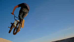 bmx車手在半空中跳躍，背景是清澈的藍天。