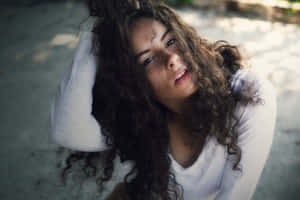 年輕女性，捲髮，在戶外若有所思地抬頭仰望。