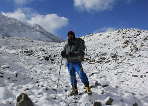 徒步旅行者帶著登山杖和背包在白雪覆蓋的山徑上，藍天白雲