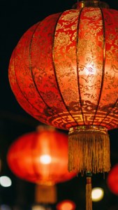 夜間發光的紅色中國燈籠，帶有裝飾圖案和流蘇。 — iPhone 5 壁紙