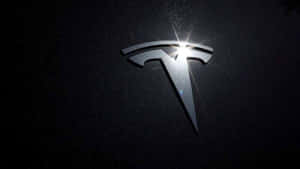 在深色表面上以明亮光線照亮的Tesla標誌 — Tesla GIF 壁紙