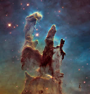在充滿星星的星雲中，宇宙柱閃耀著藍色和橙色的色調。 — Galaxy Z Flip7 FE 壁紙