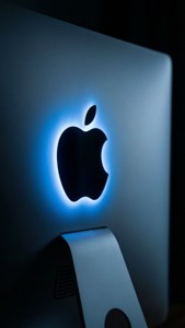 在黑暗房間中的銀色 iMac 上發光的藍色 Apple 標誌