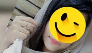 一個深色頭髮、戴著白色頭紗的人，坐在木長椅上，手持戒指微笑。