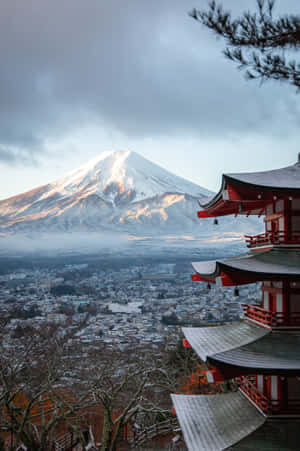 紅色寺廟俯瞰著被雪覆蓋的富士山和下方霧氣瀰漫的小鎮。