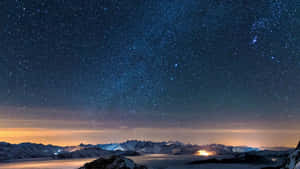 星空下，積雪的山峰與發光的地平線。