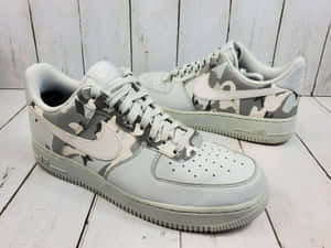白色木地板上的灰色迷彩Nike Air Force 1波鞋。