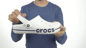 一個人拎住一隻有藍色標誌嘅白色Crocs鞋。 — 白色美學gif 壁紙