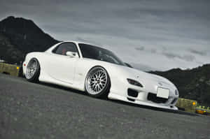 白色萬事得RX-7跑車在山路上，天空多雲