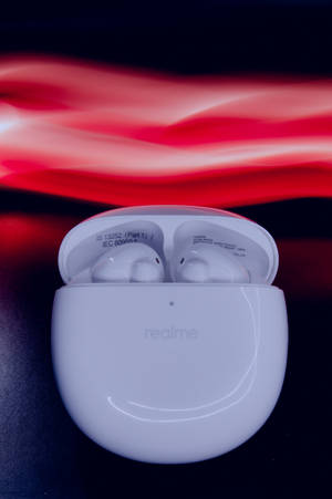 白色 realme 耳機在打開的充電盒中，帶有紅色動態模糊背景。 — Realme 壁紙