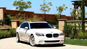 白色BMW房車停在碎石車道上，有花園和灰泥牆