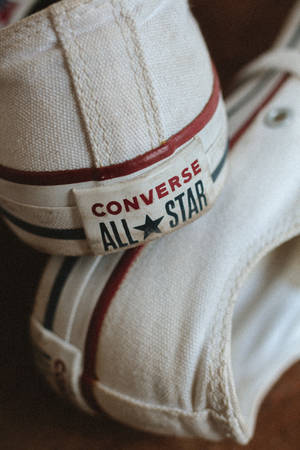 磨損的白色Converse All Star運動鞋，帶有紅色和黑色條紋。