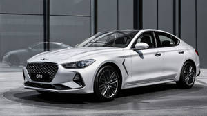 白色現代 G70 轎車在現代玻璃展廳中展示，帶有倒影。
