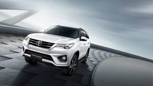 白色豐田 Fortuner SUV 在未來感灰色平台上，搭配戲劇性燈光。