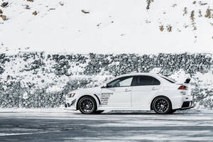 白色跑車停泊在雪路旁近石牆