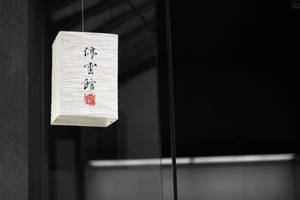 帶有黑色字元和紅色印章的白色日本燈籠懸掛在室內。
