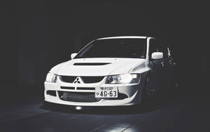 白色三菱Lancer Evolution在黑暗的攝影棚中，有聚光燈。