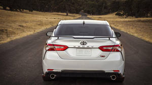 白色豐田Camry TRD房車在日落時分行駛在鄉村道路上。