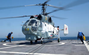 軍用直升機在航空母艦甲板上，機組人員引導它。
