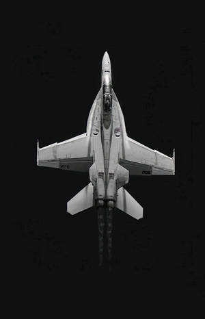 從上方俯瞰戰鬥機在黑色天空中攀升並留下排氣痕跡。