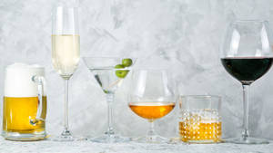 灰色紋理表面上的六種不同酒精飲品，裝在各種玻璃杯中。 — 雲石動態 壁紙