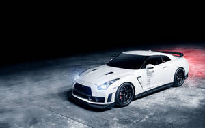 白色日產GT-R賽車，帶有黑色車輪和發光車頭燈，停在深色混凝土地板上。