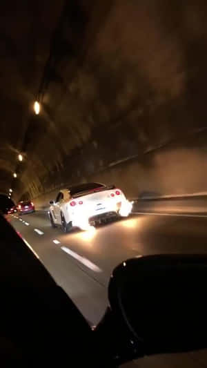 白色跑車在夜間穿過黑暗的隧道，帶有發光的尾燈。 — 汽車 壁紙