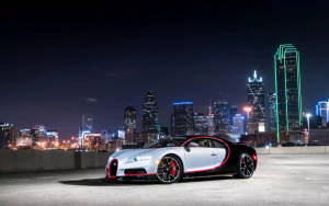 銀黑色 Bugatti 跑車在屋頂上，夜晚的城市天際線閃爍發光。