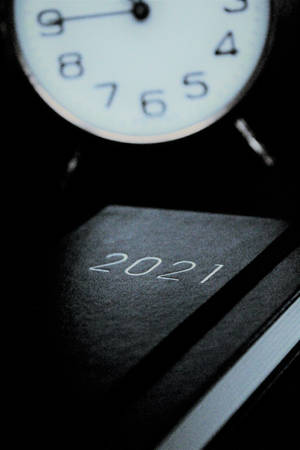 時鐘置於2021年日曆書上方，黑暗環境