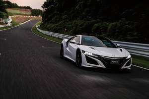 白色Acura NSX在黃昏時分的彎曲賽道上比賽