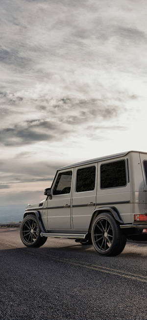 黃昏時分，一架銀色 Mercedes G-Wagen 停泊在海岸公路上。 — Galaxy S22 Ultra 壁紙