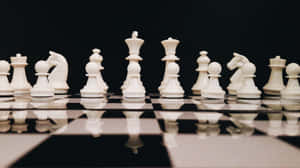 白色棋子排列在反光的棋盤上，背景為黑色。 — 國際象棋 壁紙