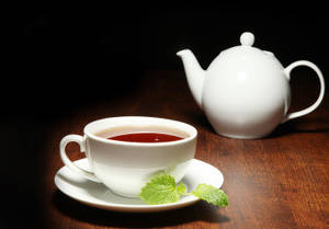 白色茶杯和茶壺配薄荷葉，木桌，聚光燈。 — 青綠色 GIF 壁紙