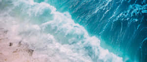 綠松石色的海浪拍打沙灘，泛起白色泡沫。